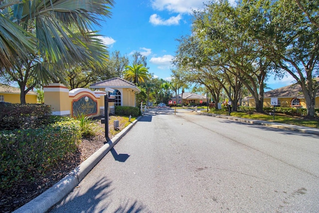 2216 Mystic Ring Loop, Poinciana, FL 34759 - view of asphalt road with curbs, traffic signs, and a gated entry