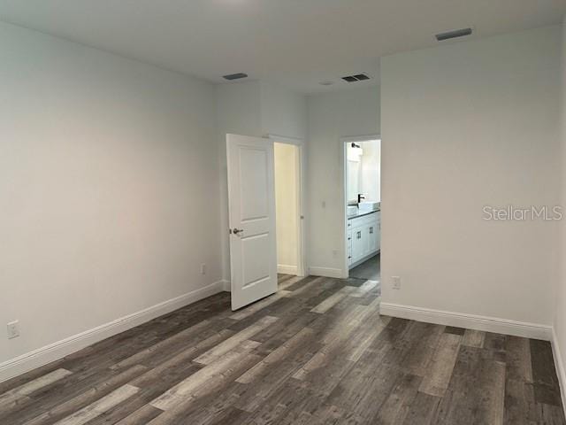 unfurnished bedroom featuring dark wood-type flooring and ensuite bath