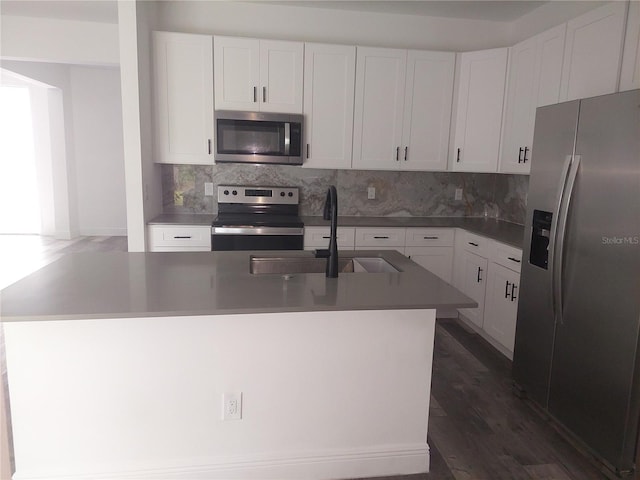 kitchen with appliances with stainless steel finishes, dark hardwood / wood-style flooring, sink, a center island with sink, and white cabinetry