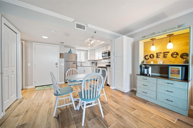 dining room featuring light hardwood / wood-style flooring, ornamental molding, and sink