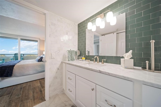 bathroom with tasteful backsplash, vanity, wood-type flooring, and tile walls