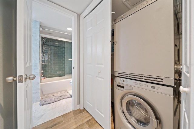 washroom with stacked washer / drying machine and light wood-type flooring