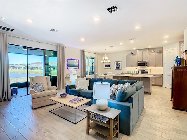 living room with a chandelier, light hardwood / wood-style flooring, a wealth of natural light, and sink