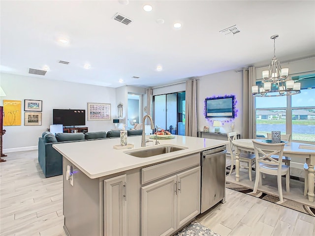 kitchen with dishwasher, sink, a chandelier, decorative light fixtures, and a center island with sink