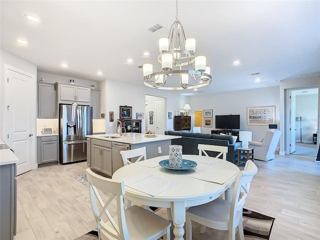 dining area with sink, an inviting chandelier, and light wood-type flooring