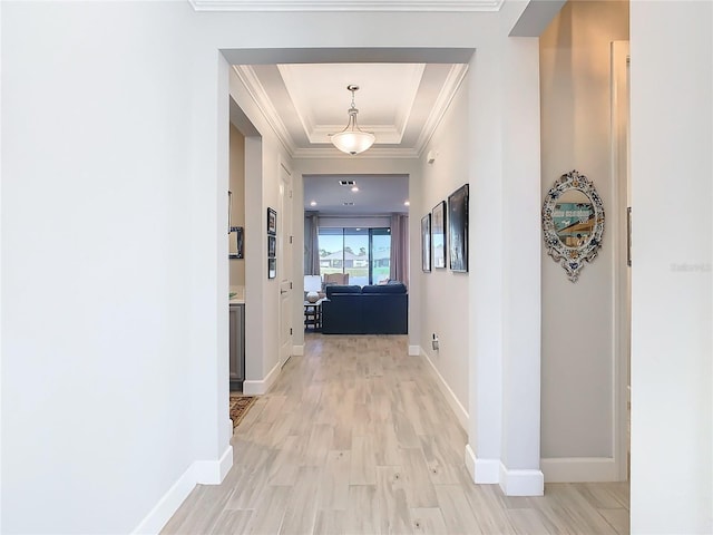 hall with light hardwood / wood-style floors and a raised ceiling