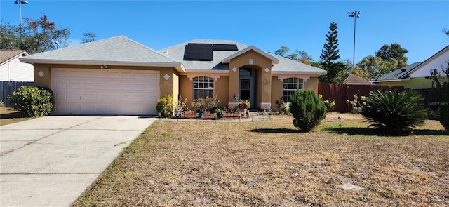 view of front of property featuring a garage, solar panels, and a front yard