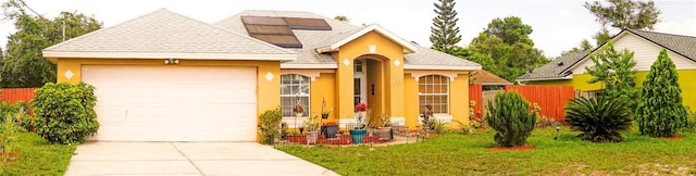 1053 Hemingway Dr, Deltona, FL 32725 - view of front of home featuring stucco siding, an attached garage, driveway, roof mounted solar panels, and roof with shingles