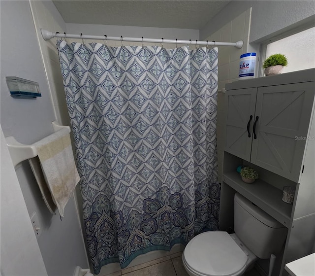 bathroom featuring tile patterned floors, a shower with shower curtain, a textured ceiling, and toilet