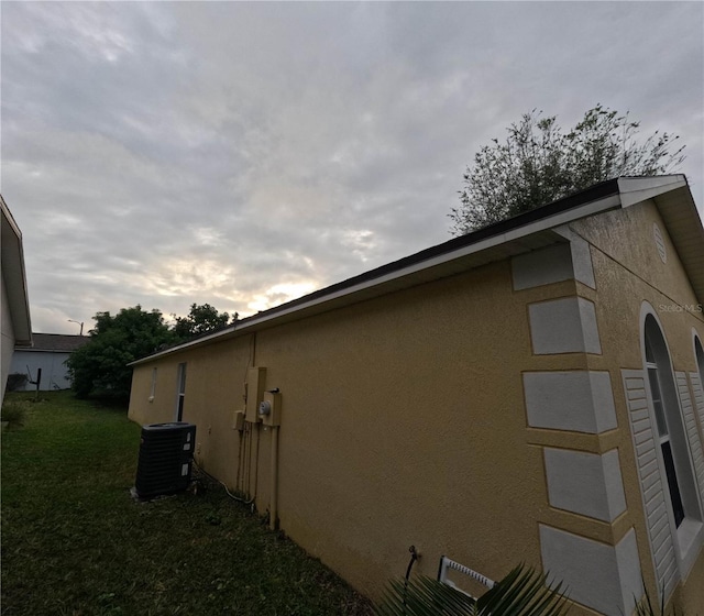 view of side of property featuring a lawn and cooling unit