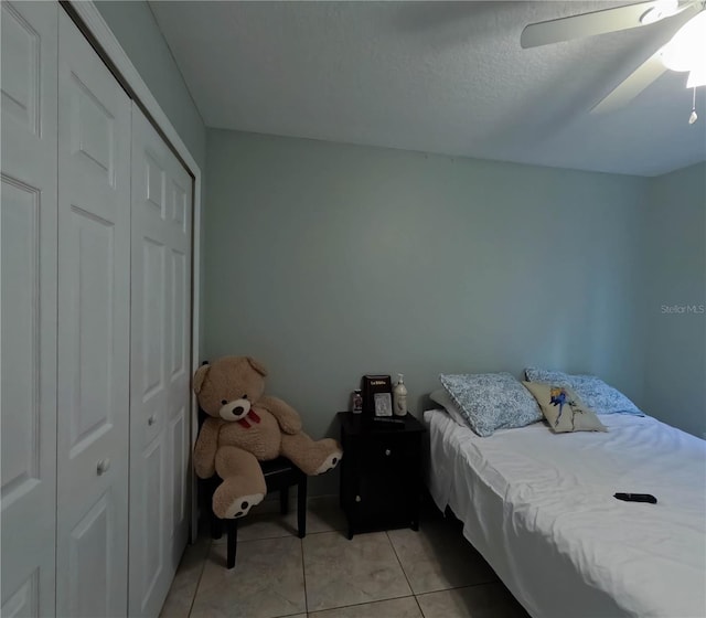 tiled bedroom featuring ceiling fan, a textured ceiling, and a closet