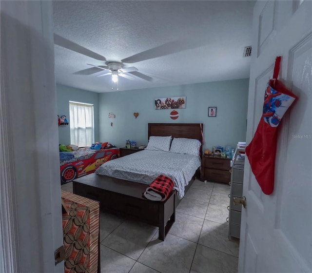 bedroom featuring ceiling fan, light tile patterned flooring, and a textured ceiling