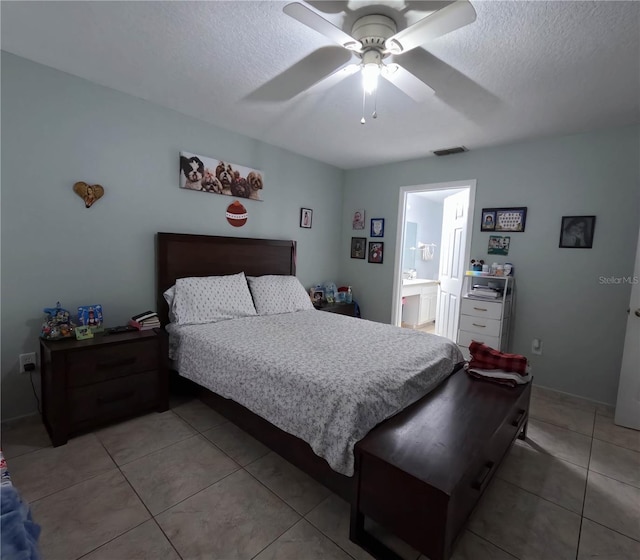 bedroom with connected bathroom, ceiling fan, light tile patterned flooring, and a textured ceiling