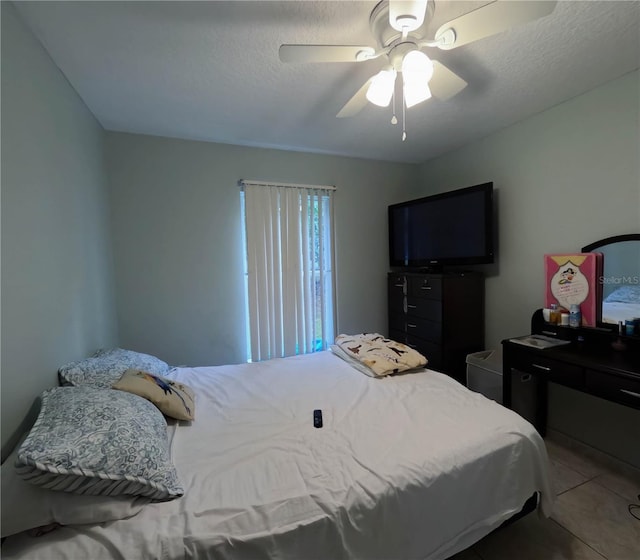 tiled bedroom with ceiling fan and a textured ceiling