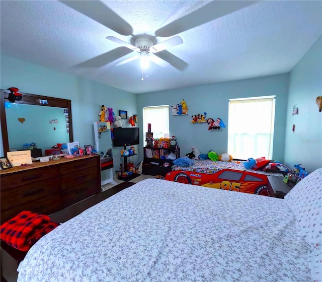 bedroom with multiple windows, a textured ceiling, and ceiling fan