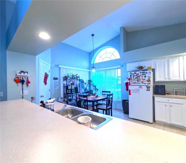 kitchen with light tile patterned floors, white cabinets, pendant lighting, white fridge, and sink