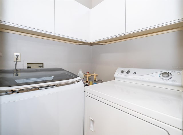 clothes washing area with cabinets and washer and dryer