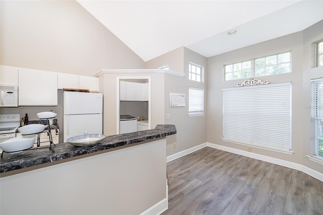 1423 Farrindon Cir Unit 1423, Lake Mary, FL 32746 - kitchen featuring white appliances, a high ceiling, white cabinets, washer and clothes dryer, and light wood-style floors