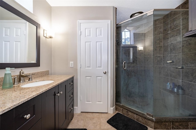 bathroom featuring tile patterned flooring, vanity, an enclosed shower, and a textured ceiling