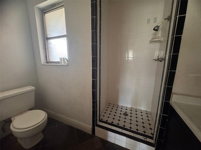 bathroom with tiled shower, tile patterned flooring, and toilet