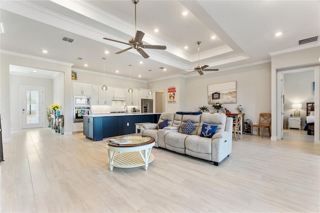 living room featuring ceiling fan, sink, and ornamental molding