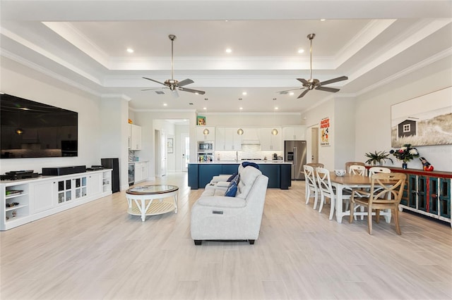 living room featuring a tray ceiling, crown molding, and light hardwood / wood-style floors