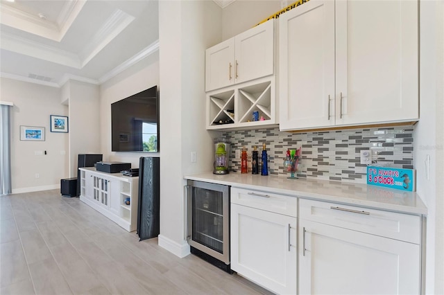 bar featuring white cabinets, ornamental molding, backsplash, and beverage cooler