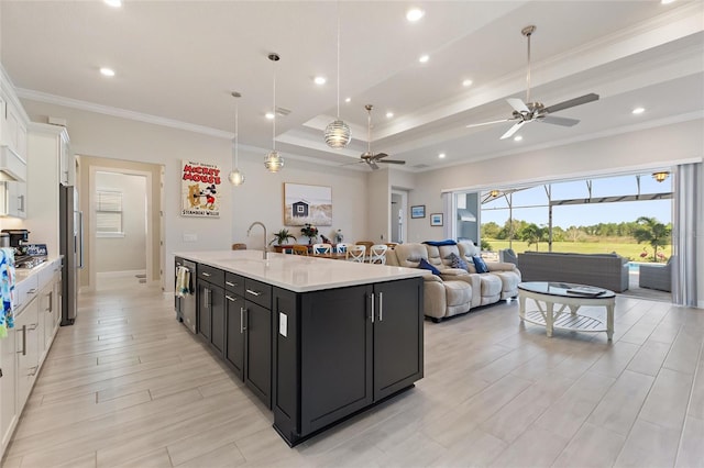 kitchen featuring a kitchen island with sink, ceiling fan, ornamental molding, decorative light fixtures, and white cabinetry