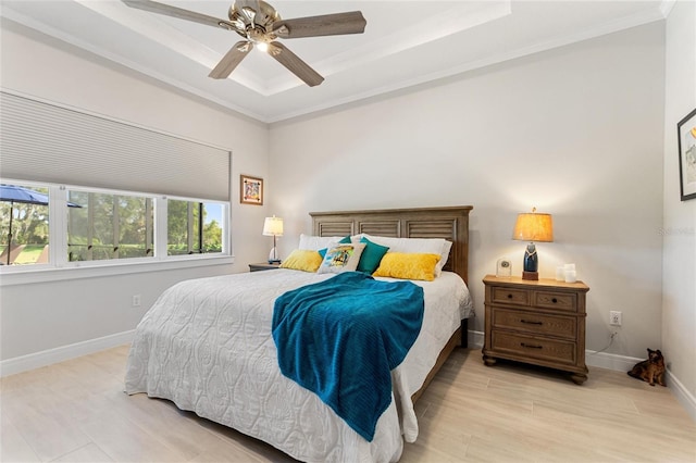 bedroom with light hardwood / wood-style floors, a raised ceiling, ceiling fan, and crown molding