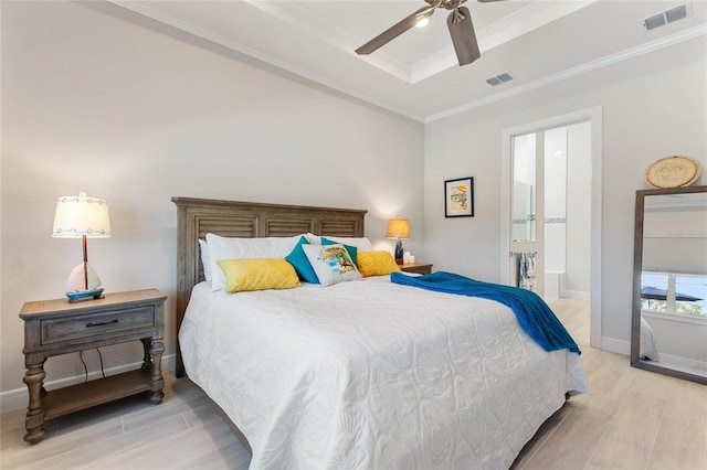 bedroom with ensuite bathroom, ornamental molding, a raised ceiling, ceiling fan, and light hardwood / wood-style floors