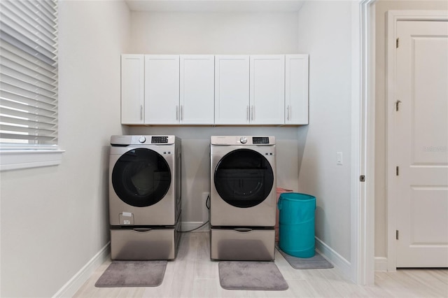 laundry area featuring washer and dryer, cabinets, and light hardwood / wood-style flooring