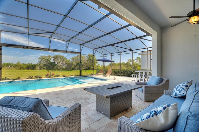 view of swimming pool with outdoor lounge area, a patio, glass enclosure, and ceiling fan