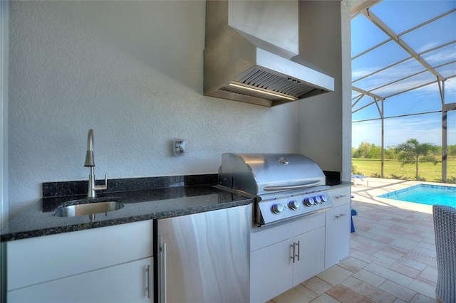 view of patio featuring glass enclosure, a grill, exterior kitchen, and sink