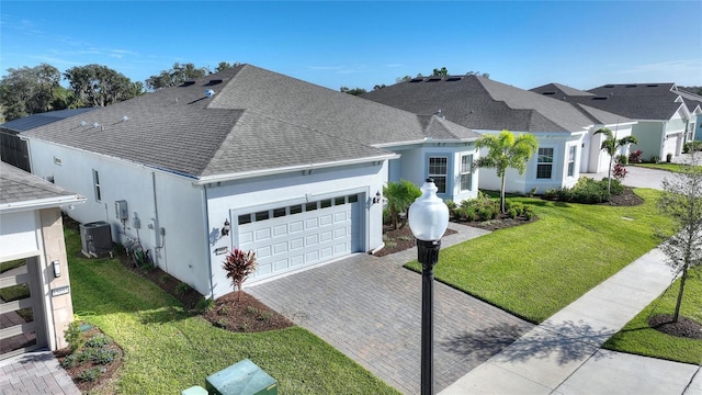 view of front facade featuring a garage, central air condition unit, and a front lawn