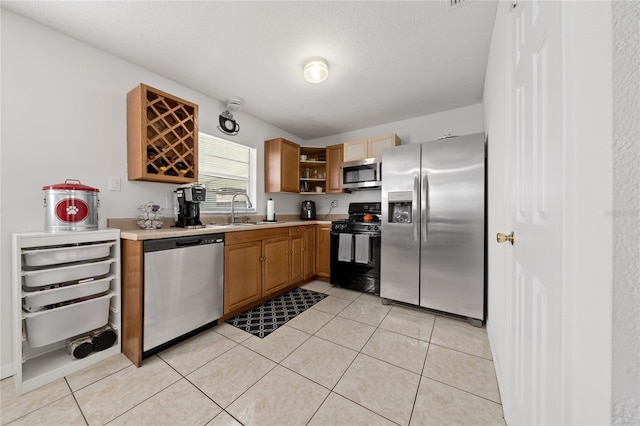 kitchen featuring sink, light tile patterned floors, a textured ceiling, and appliances with stainless steel finishes