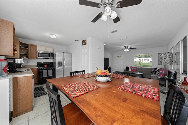 dining area with ceiling fan, light tile patterned floors, and a textured ceiling