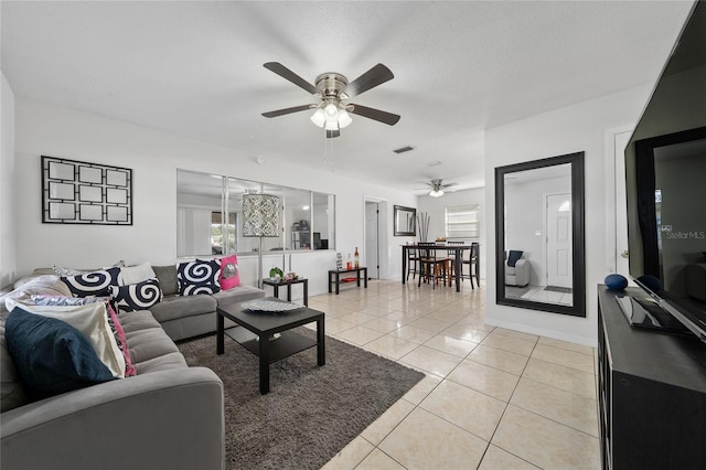 living room featuring ceiling fan, light tile patterned flooring, and a textured ceiling