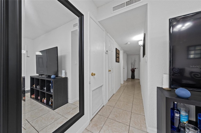 corridor featuring light tile patterned floors and a textured ceiling