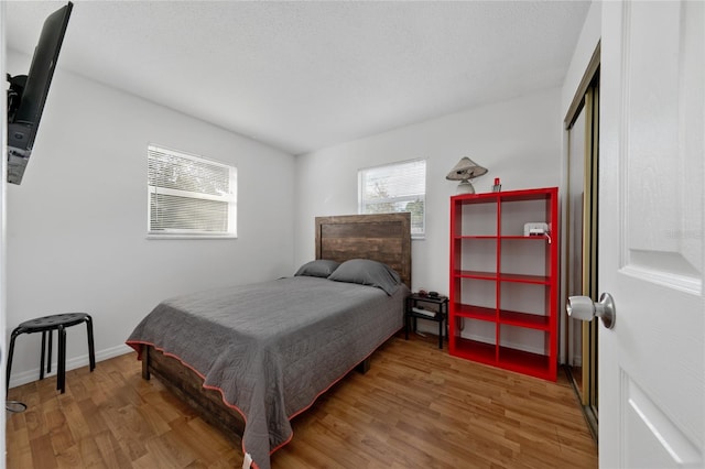 bedroom with wood-type flooring and a wall unit AC