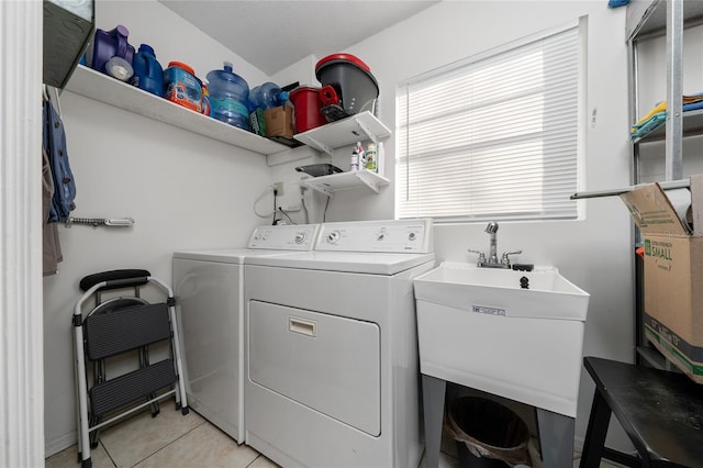 laundry room featuring light tile patterned floors, washing machine and dryer, and sink