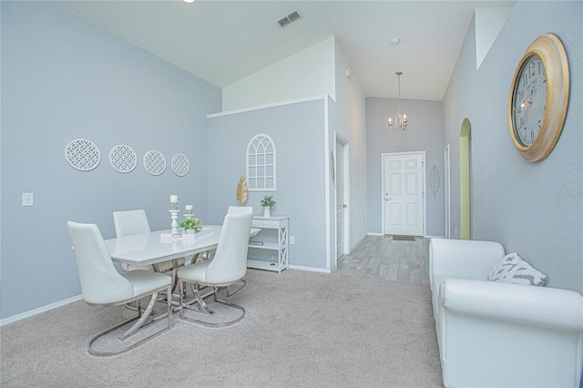 dining room featuring high vaulted ceiling, light colored carpet, and an inviting chandelier