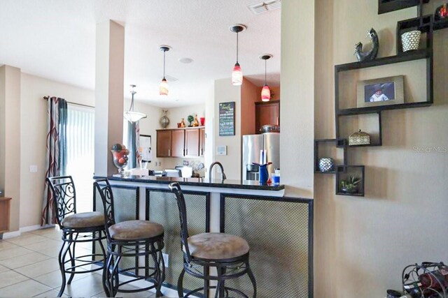 kitchen with kitchen peninsula, stainless steel fridge with ice dispenser, hanging light fixtures, and a kitchen breakfast bar