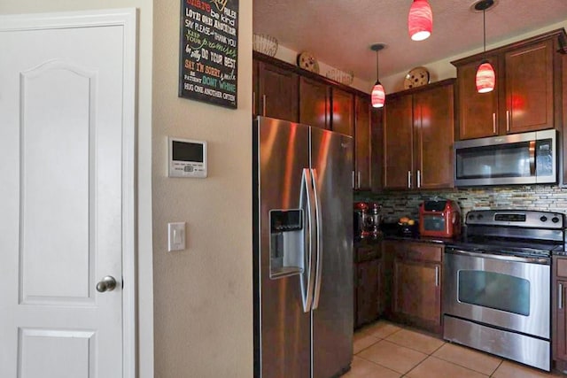 kitchen with backsplash, a textured ceiling, stainless steel appliances, light tile patterned floors, and decorative light fixtures