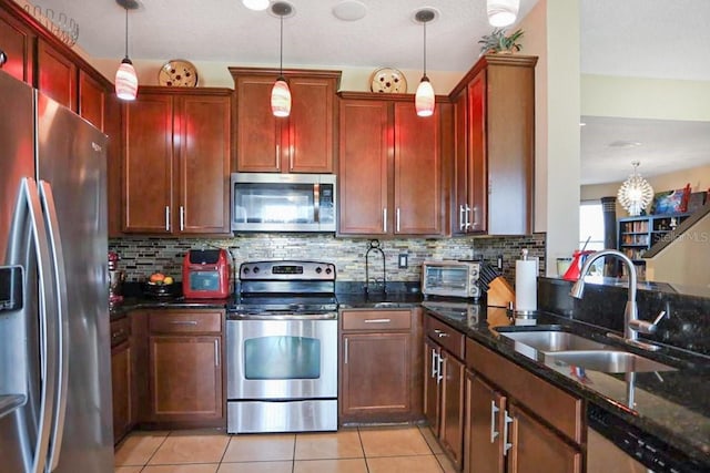 kitchen featuring tasteful backsplash, stainless steel appliances, sink, decorative light fixtures, and dark stone countertops