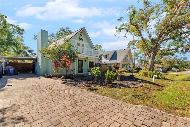 view of front of home with a front yard, a balcony, and a carport