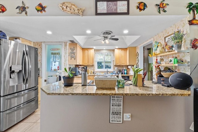 kitchen with light stone countertops, ceiling fan, stainless steel refrigerator with ice dispenser, a tray ceiling, and light brown cabinetry