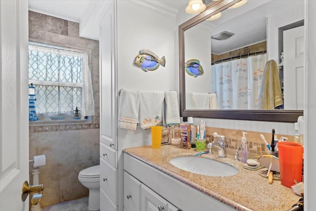 bathroom featuring vanity, toilet, tile walls, and crown molding