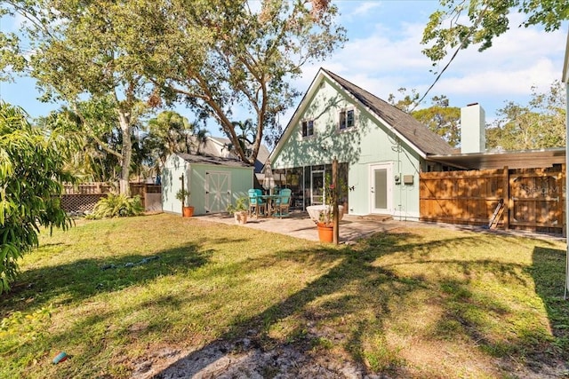 rear view of house with a yard, a patio, and a storage shed