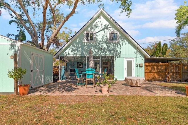 rear view of property with a patio area, a yard, and a storage unit