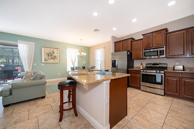 kitchen featuring a center island with sink, a wealth of natural light, a breakfast bar, and appliances with stainless steel finishes